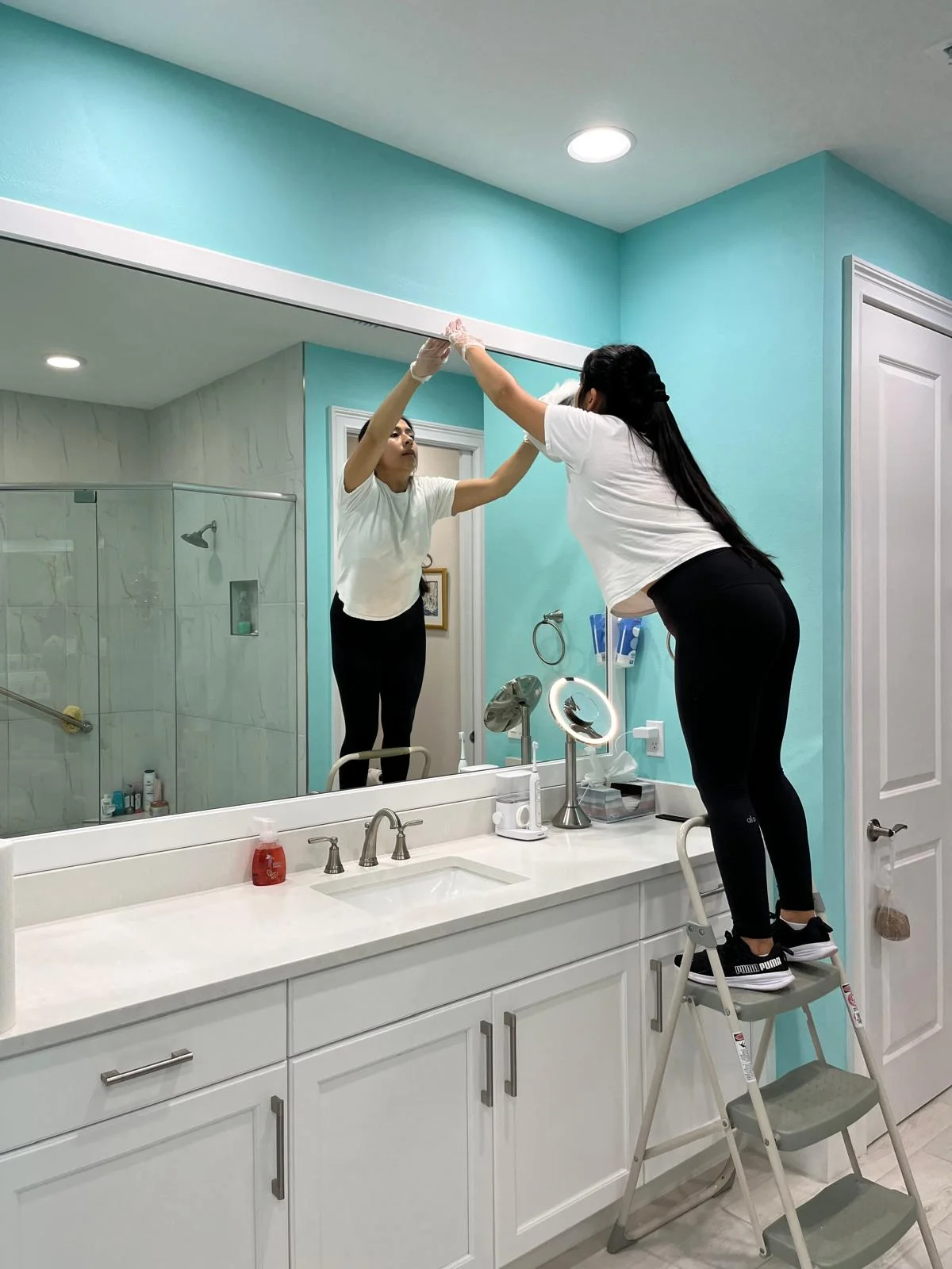 A member of the Conii's Cleaning team detailing a bathroom mirror.