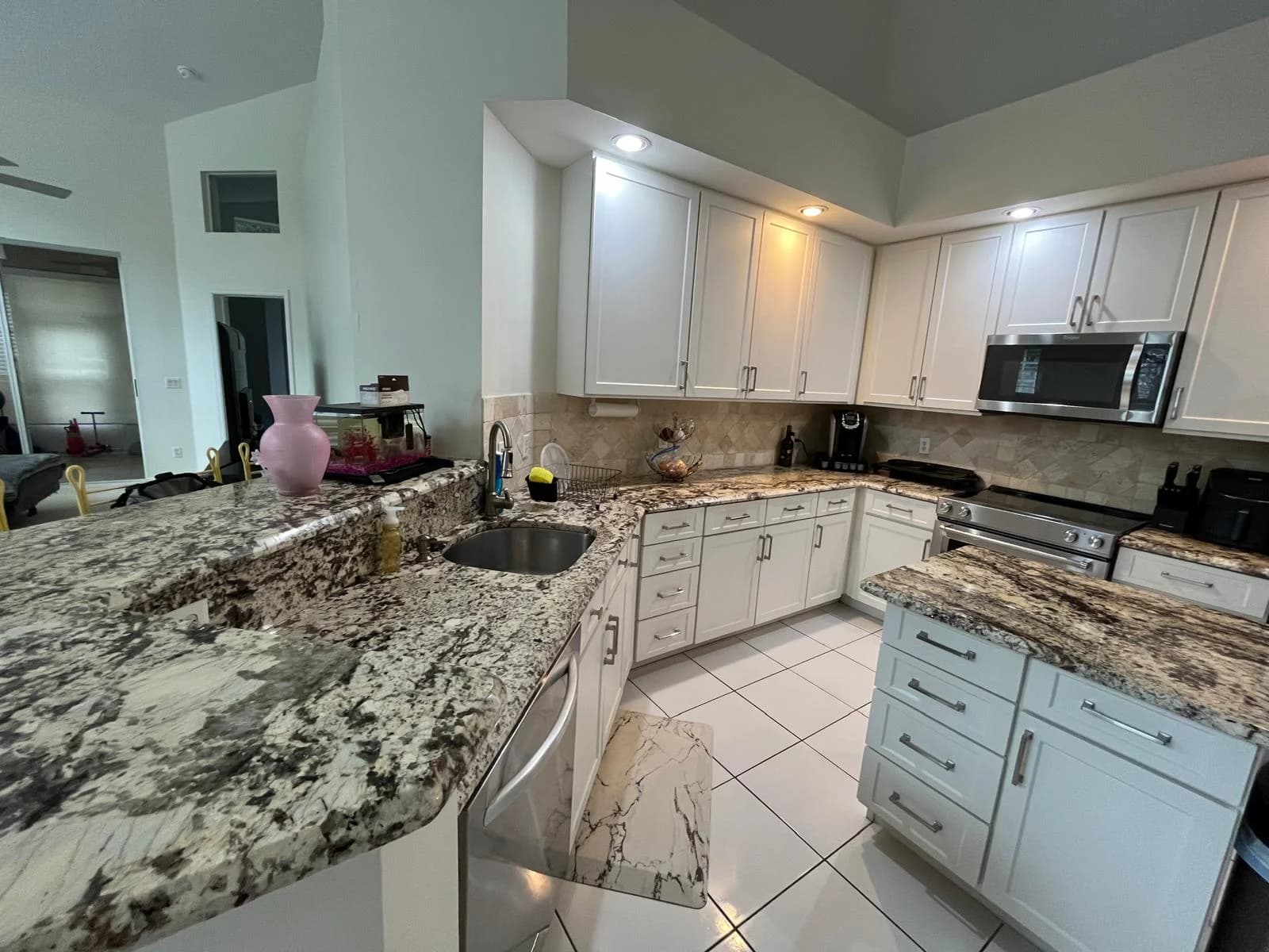 A bright kitchen with white cabinets and granite counters, spotless.