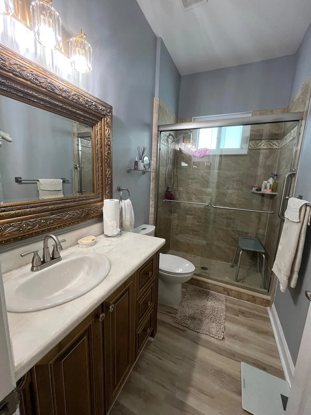 A bathroom with a framed mirror and glass shower, spotless.