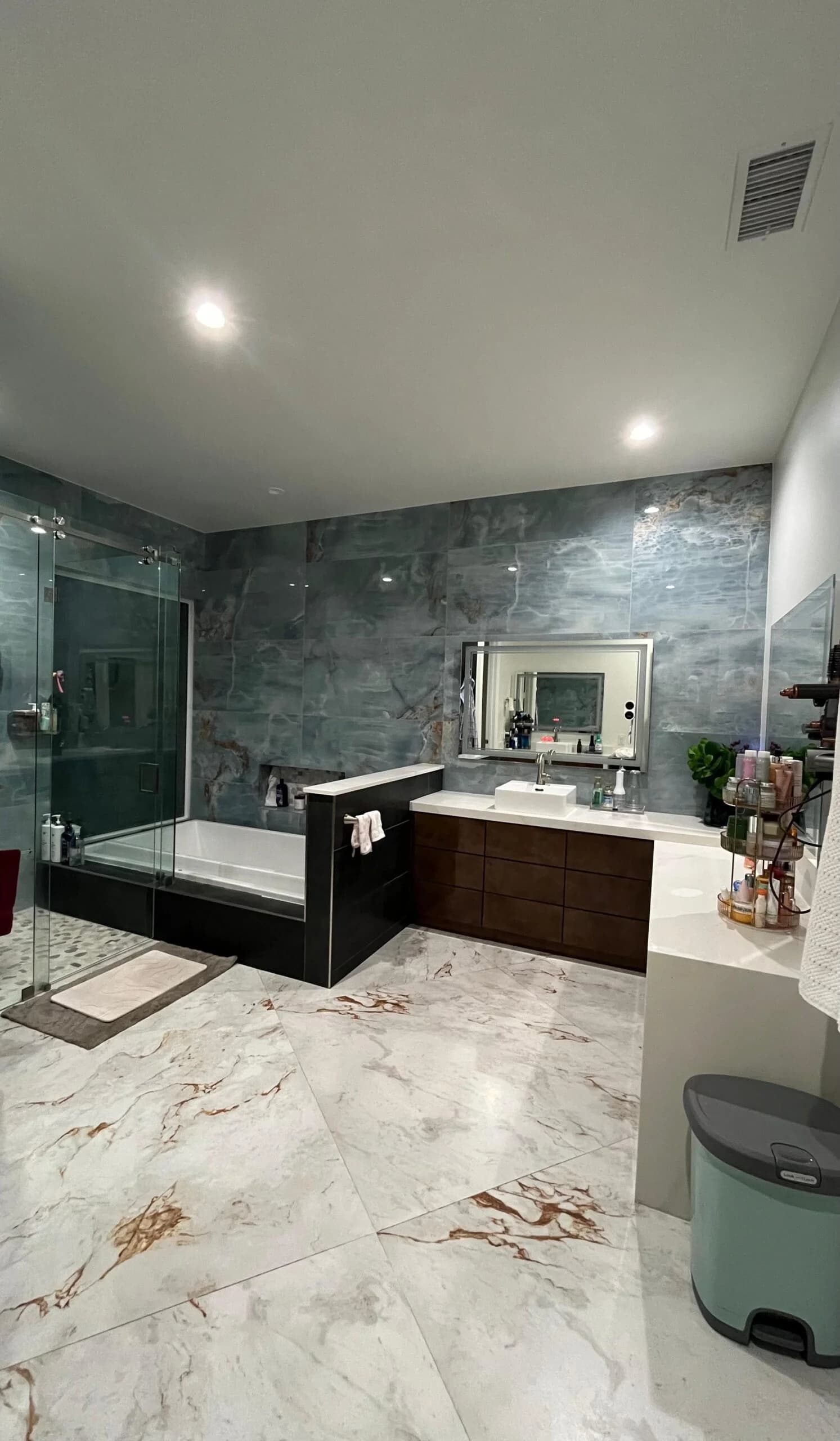 A modern marble-tile bathroom with glass shower and soaking tub, spotless.
